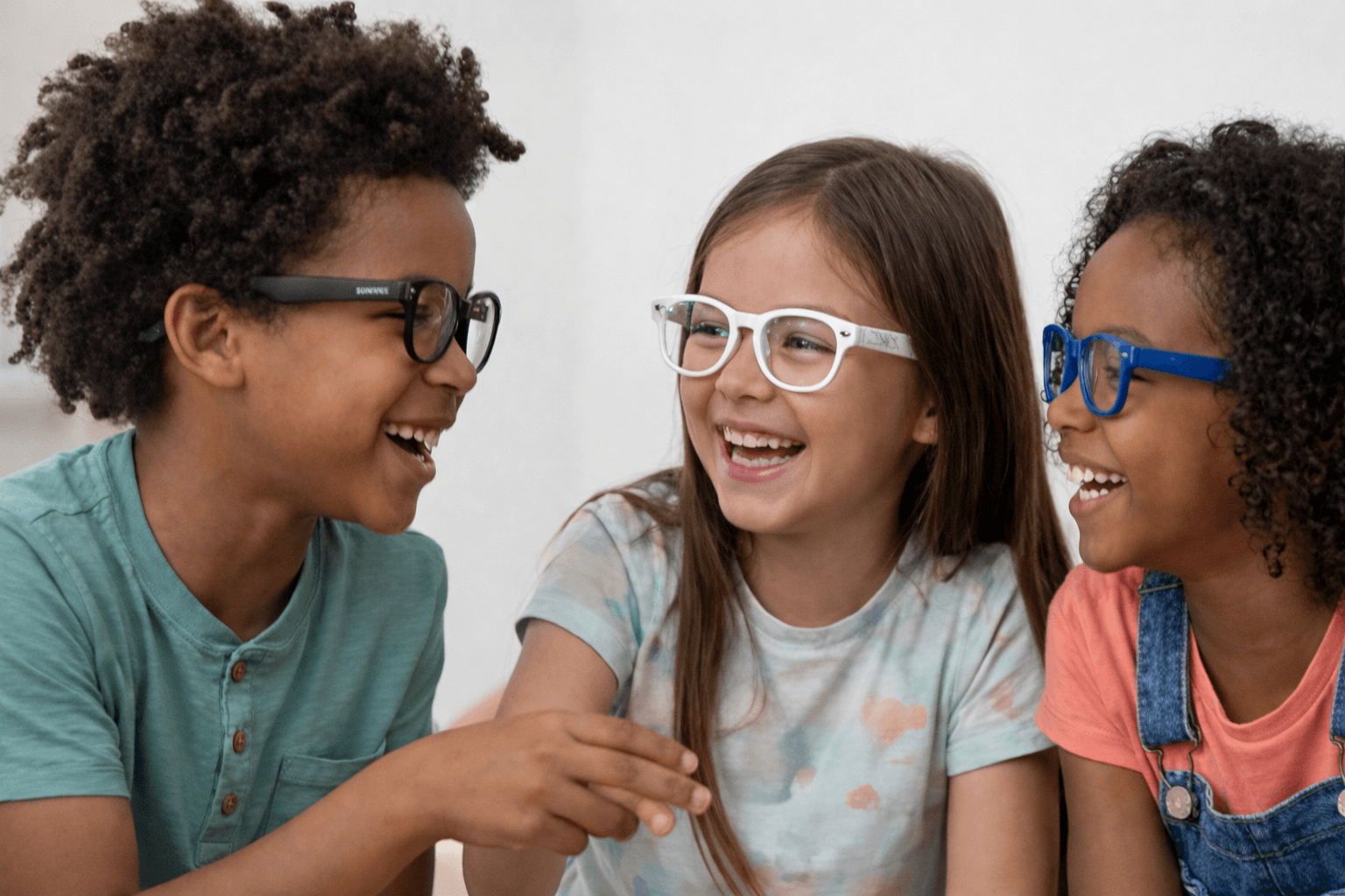 Three kids laughing together wearing Shiro glasses in different colors